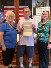 Carol Dunn (left) and Sarah Swendsen (right) with Tom Rue who holds the Skinner document.